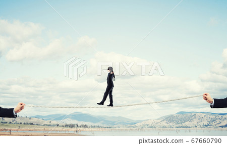 Business concept of risk support and assistance with man balancing on rope Business concept of risk support and assistance with man balancing on rope 67660790