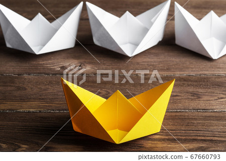 Business leadership concept with white and color paper boats on wooden table Business leadership concept with white and color paper boats on wooden table 67660793