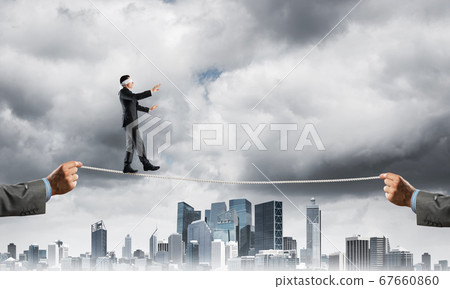 Business concept of risk support and assistance with man balancing on rope 67660860
