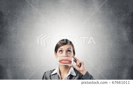 Woman covering her mouth with smartphone 67661011