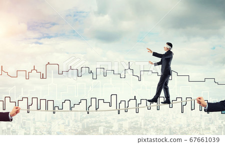 Business concept of risk support and assistance with man balancing on rope 67661039