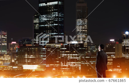 Businessman viewing night glowing city Businessman viewing night glowing city 67661865