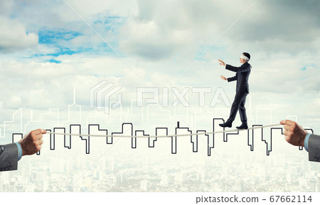 Business concept of risk support and assistance with man balancing on rope Business concept of risk support and assistance with man balancing on rope 67662114