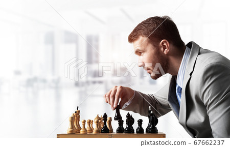 Concentrated businessman playing chess game 67662237