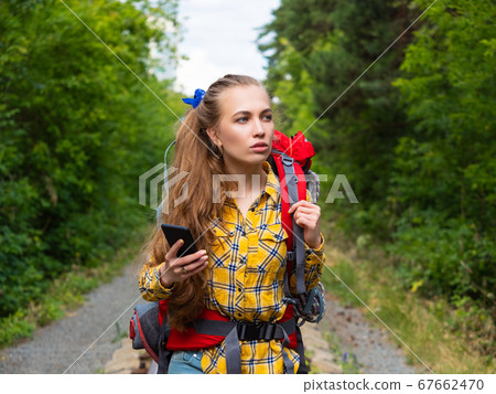 Portrait of a woman, who lost in forest. She using mobile GPS map. Portrait of a woman, who lost in forest. She using mobile GPS map. 67662470