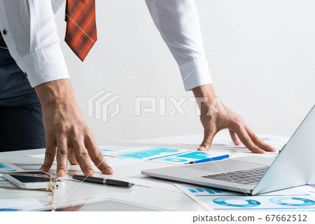 Businessman in suit and tie standing near desk Businessman in suit and tie standing near desk 67662512