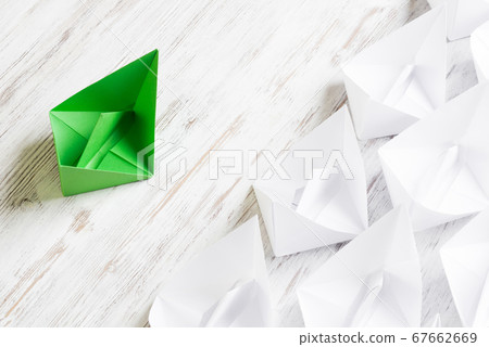 Business leadership concept with white and color paper boats on wooden table 67662669