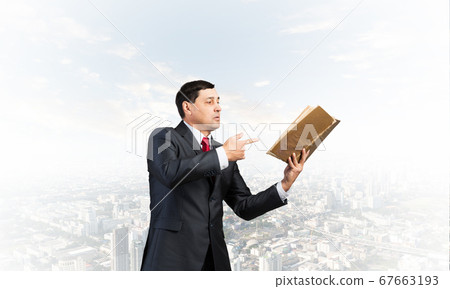 Senior businessman finger pointing into open book 67663193