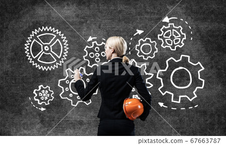 Businesswoman draws gears mechanism on blackboard 67663787