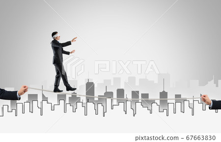 Business concept of risk support and assistance with man balancing on rope 67663830