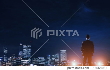 Businessman viewing night glowing city Businessman viewing night glowing city 67664085
