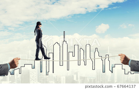Business concept of risk support and assistance with man balancing on rope Business concept of risk support and assistance with man balancing on rope 67664137