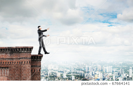 Danger and risk concept with businessman making step from edge Danger and risk concept with businessman making step from edge 67664141