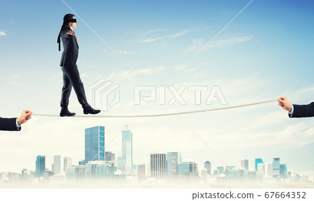 Business concept of risk support and assistance with man balancing on rope 67664352