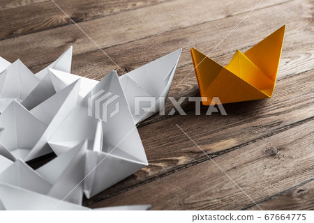 Business leadership concept with white and color paper boats on wooden table Business leadership concept with white and color paper boats on wooden table 67664775