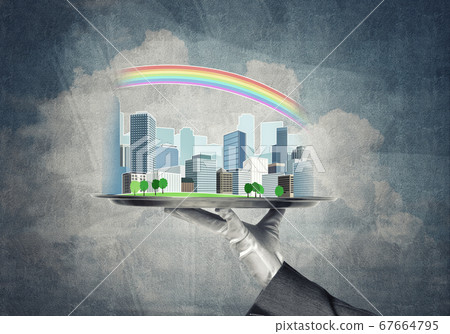 Hand holding metal tray with modern city model against concrete background Hand holding metal tray with modern city model against concrete background 67664795