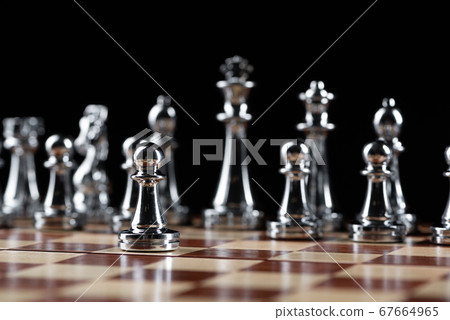 Steel chess figures standing on wooden chessboard 67664965