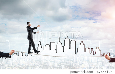 Business concept of risk support and assistance with man balancing on rope 67665192