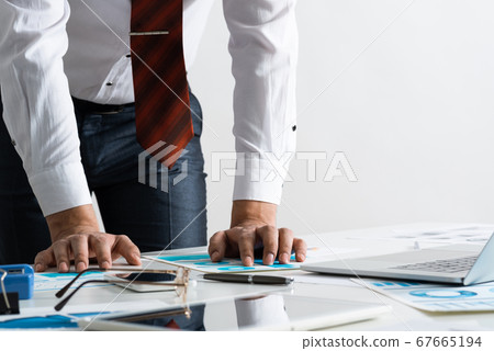 Businessman in suit and tie standing near desk Businessman in suit and tie standing near desk 67665194