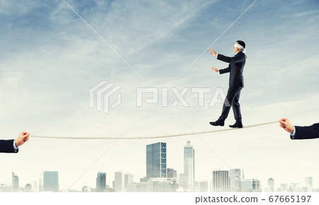 Business concept of risk support and assistance with man balancing on rope 67665197