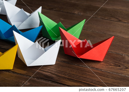 Business leadership concept with white and color paper boats on wooden table Business leadership concept with white and color paper boats on wooden table 67665207