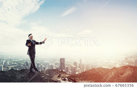 Young businessman in blindfold walking carefully and cityscape at background Young businessman in blindfold walking carefully and cityscape at background 67665356