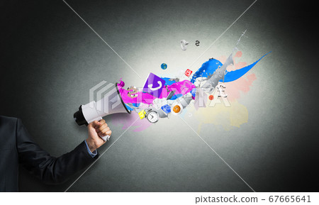 Businessman hand holding megaphone on wall Businessman hand holding megaphone on wall 67665641