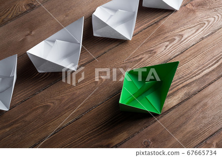 Business leadership concept with white and color paper boats on wooden table 67665734