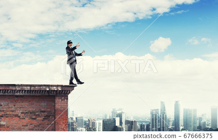Danger and risk concept with businessman making step from edge Danger and risk concept with businessman making step from edge 67666375