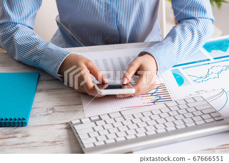 Business lady sitting at desk with mobile phone Business lady sitting at desk with mobile phone 67666551