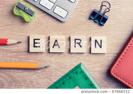 Office stuff and earn word spelled with wooden blocks on workplace Office stuff and earn word spelled with wooden blocks on workplace 67666552