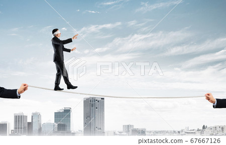 Business concept of risk support and assistance with man balancing on rope Business concept of risk support and assistance with man balancing on rope 67667126