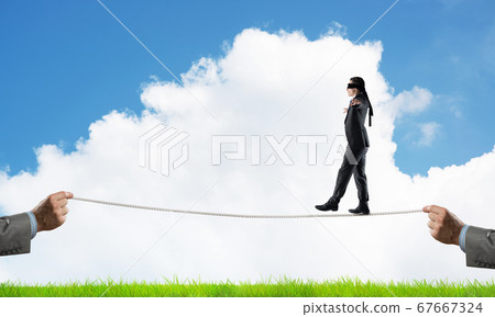 Business concept of risk support and assistance with man balancing on rope 67667324