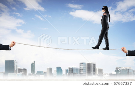 Business concept of risk support and assistance with man balancing on rope Business concept of risk support and assistance with man balancing on rope 67667327