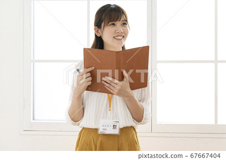 Young woman looking at a leather notebook by the window Young woman looking at a leather notebook by the window 67667404