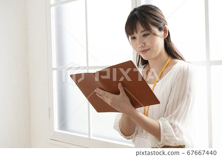 年輕女子看著窗外的皮革筆記本 年輕女子看著窗外的皮革筆記本 67667440