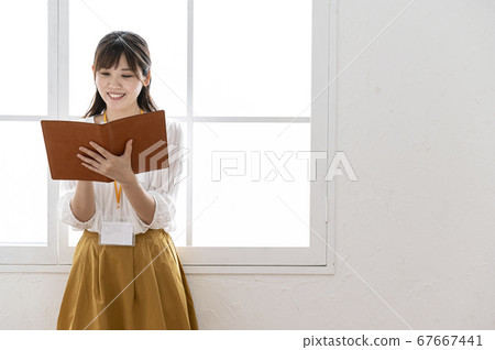 年輕女子看著窗外的皮革筆記本 年輕女子看著窗外的皮革筆記本 67667441