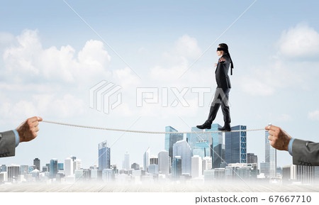 Business concept of risk support and assistance with man balancing on rope Business concept of risk support and assistance with man balancing on rope 67667710