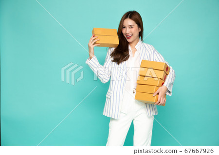 Happy Asian woman smiling and holding package parcel box isolated on light green background Happy Asian woman smiling and holding package parcel box isolated on light green background 67667926