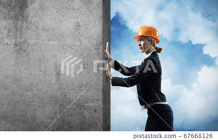 Beautiful woman architect pushing concrete wall 67668126