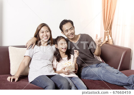 Young asian family watching TV together at home Young asian family watching TV together at home 67668459