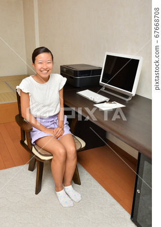 A girl sitting at a computer desk 67668708