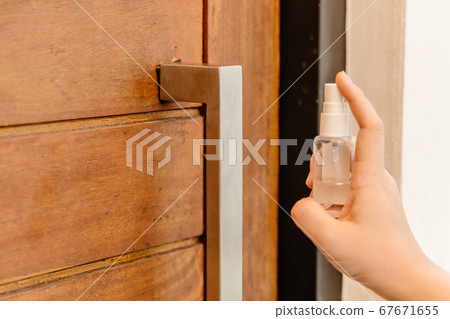 Closeup using alcohol disinfectant spray cleaning door handle for preventing spreading of virus Closeup using alcohol disinfectant spray cleaning door handle for preventing spreading of virus 67671655
