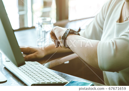 Businesswoman working on desk looking check meeting time on her wrist watch for schedule remind 67671659