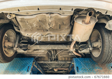 under old car closeup rear wheel axle suspension and exhaust chamber silencer muffler under old car closeup rear wheel axle suspension and exhaust chamber silencer muffler 67671660