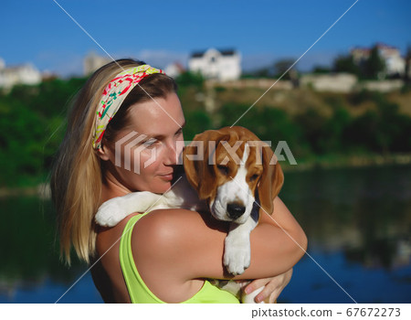 portrait of a young woman with a beagle puppy in her arms portrait of a young woman with a beagle puppy in her arms 67672273