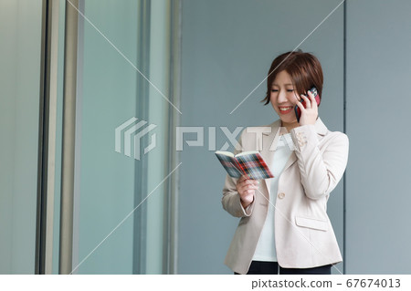 A woman calling while looking at the schedule book 67674013