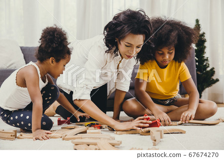 Mother parent playing with children learning to solve puzzle toy at home apartment 67674270