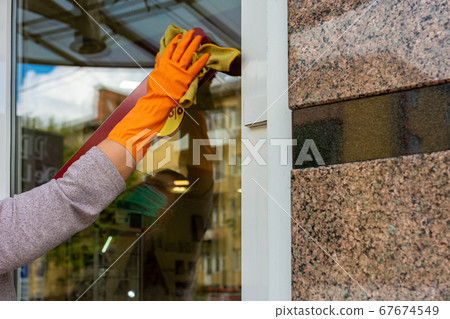Cleaner wipes the storefront and doors during a 67674549