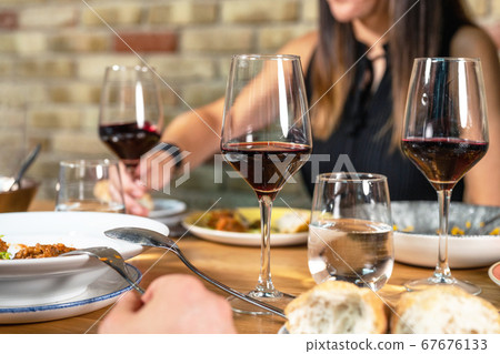 Unrecognizable Group of friends eating together and drinking wine in a restaurant. Unrecognizable Group of friends eating together and drinking wine in a restaurant. 67676133